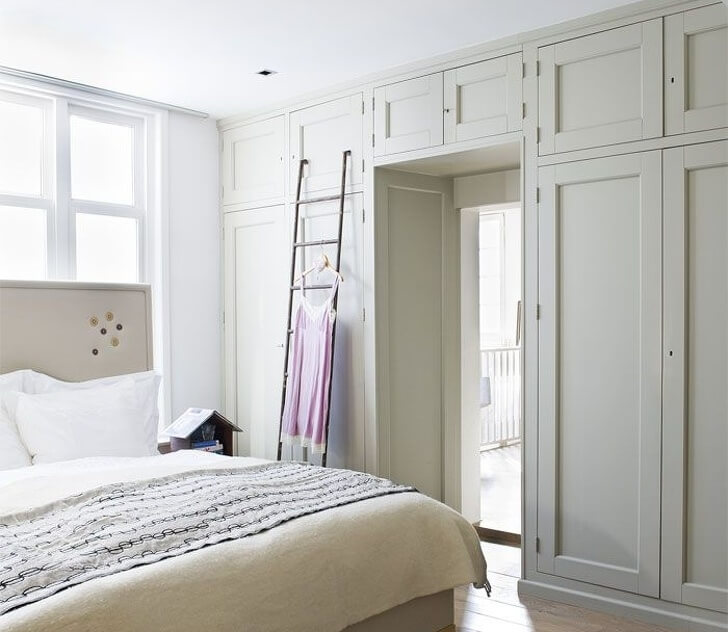 Hình ảnh phòng ngủ thoáng sáng với tủ lưu trữ màu trắng hai bên cửa ra vào