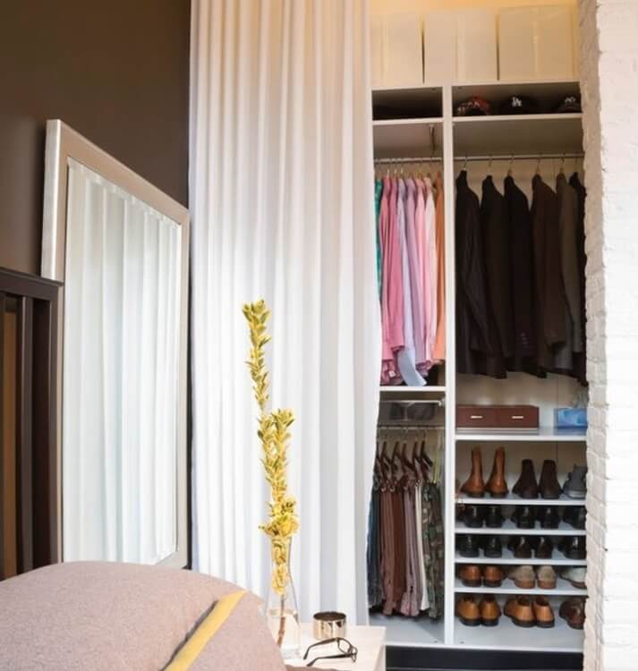 Hình ảnh cận cảnh một góc tủ quần áo mở được giấu gọn sau rèm cửa màu trắng