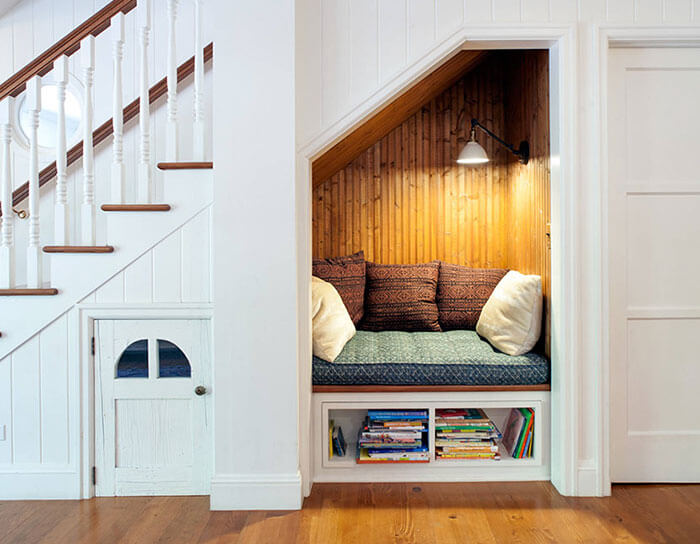 Hình ảnh góc đọc sách ở gầm cầu thang với chỗ ngồi ốp gỗ, gối tựa êm ái
