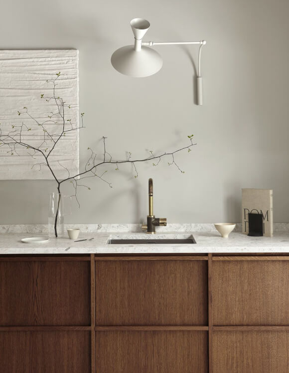 Hình ảnh một góc phòng bếp với bồn rửa bát, bề mặt ốp đá màu rắng, bình cây trang trí