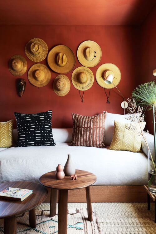 Hình ảnh phòng khách nhỏ ấn tượng với tường màu đỏ cam, trang trí bắt mắt, ghế sofa kiêm giường ngủ khi cần, bàn trà đôi bằng gỗ