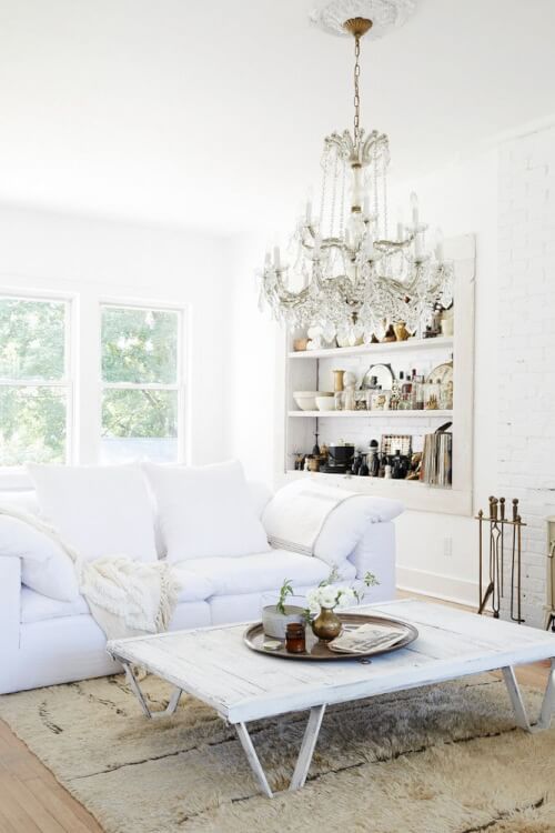 Hình ảnh phòng khách nhỏ tông màu trắng chủ đạo với điểm nhấn ấn tượng là bộ đèn chùm pha lê lớn