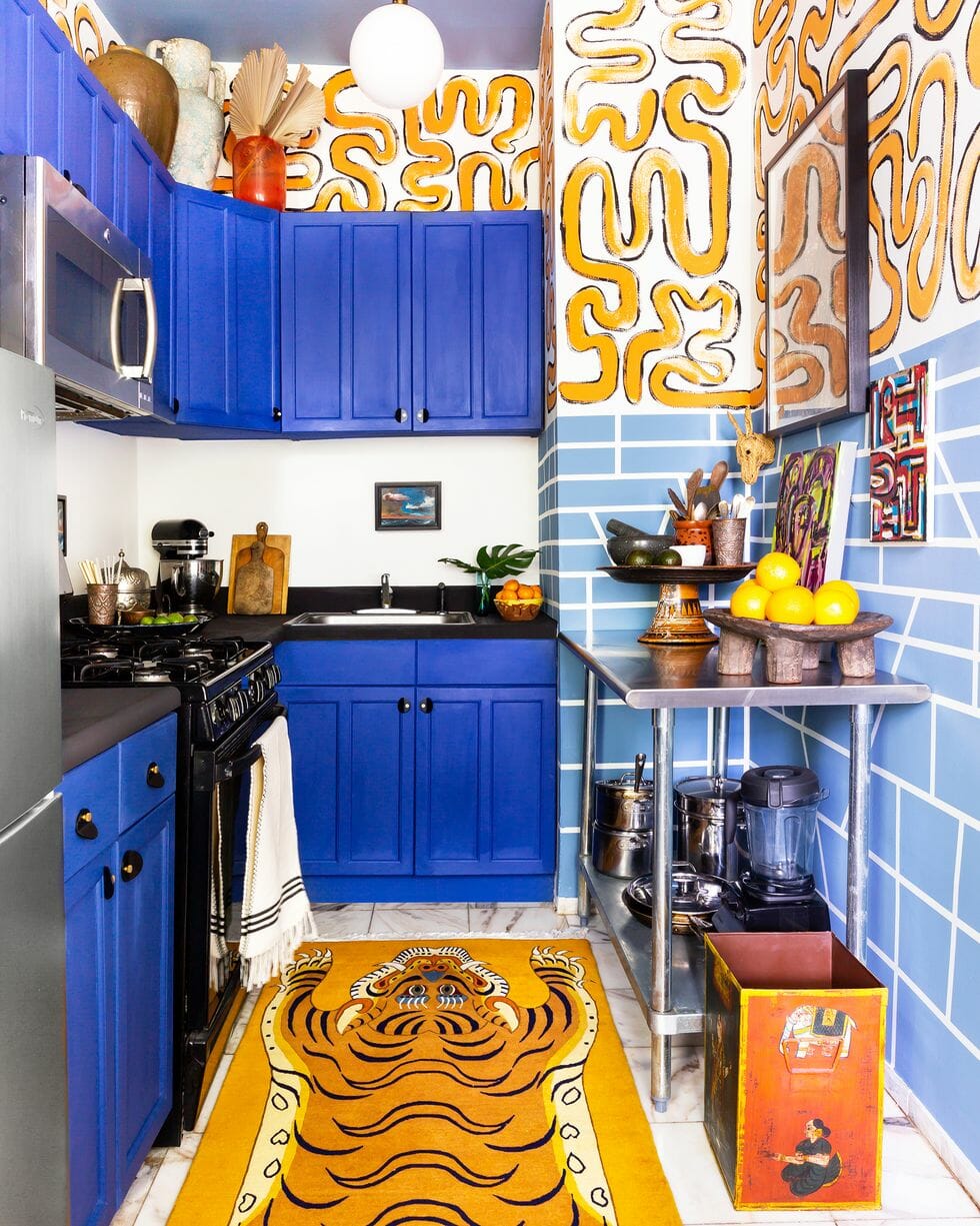 hình ảnh phòng bếp ấn tượng với hệ tủ màu xanh coban, thảm trải hình động vật, các chi tiết trang trí màu vàng trên tường nhà