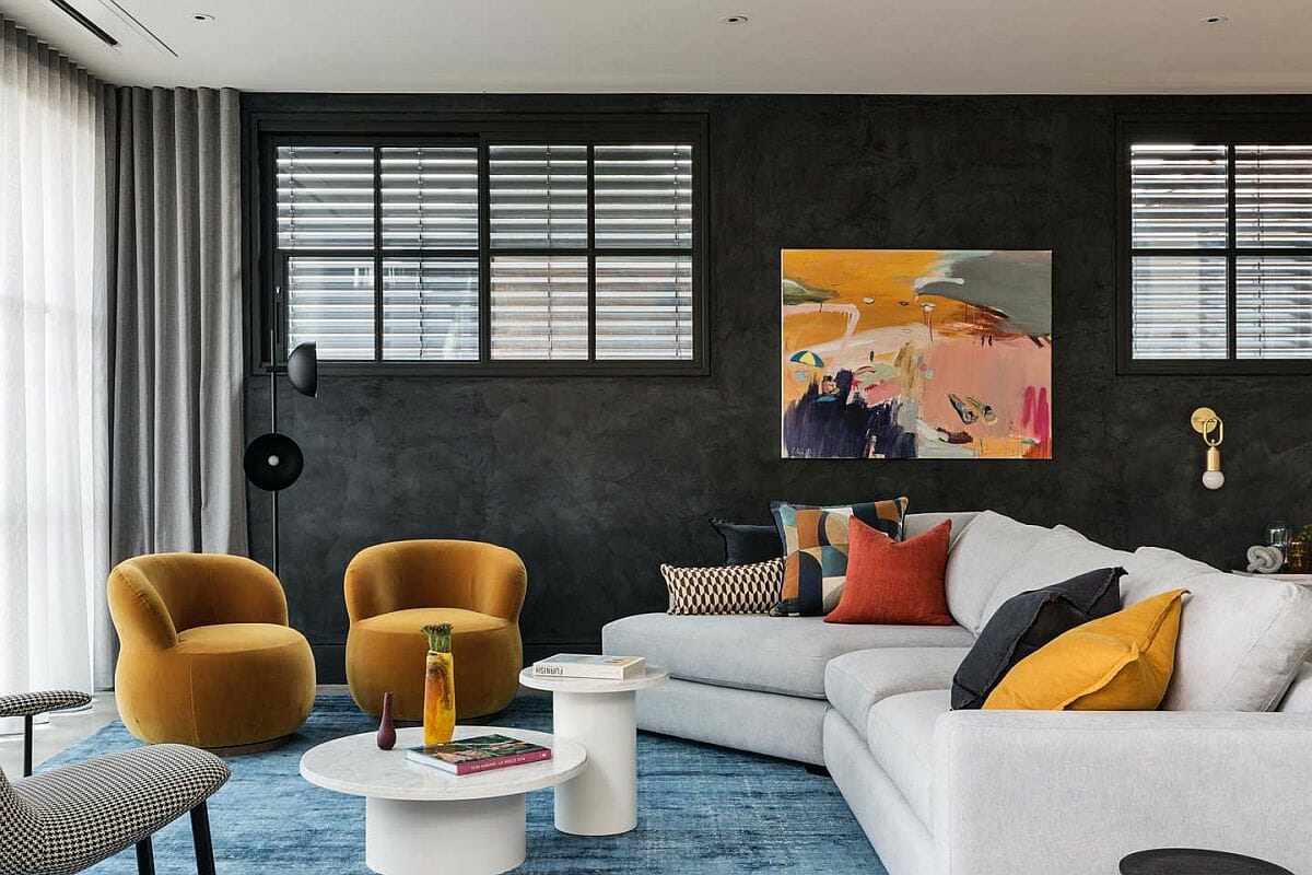 hình ảnh phòng khách với bức tường sơn đen, ghế sofa màu trắng, ghế bành và gối tựa màu vàng rực rỡ
