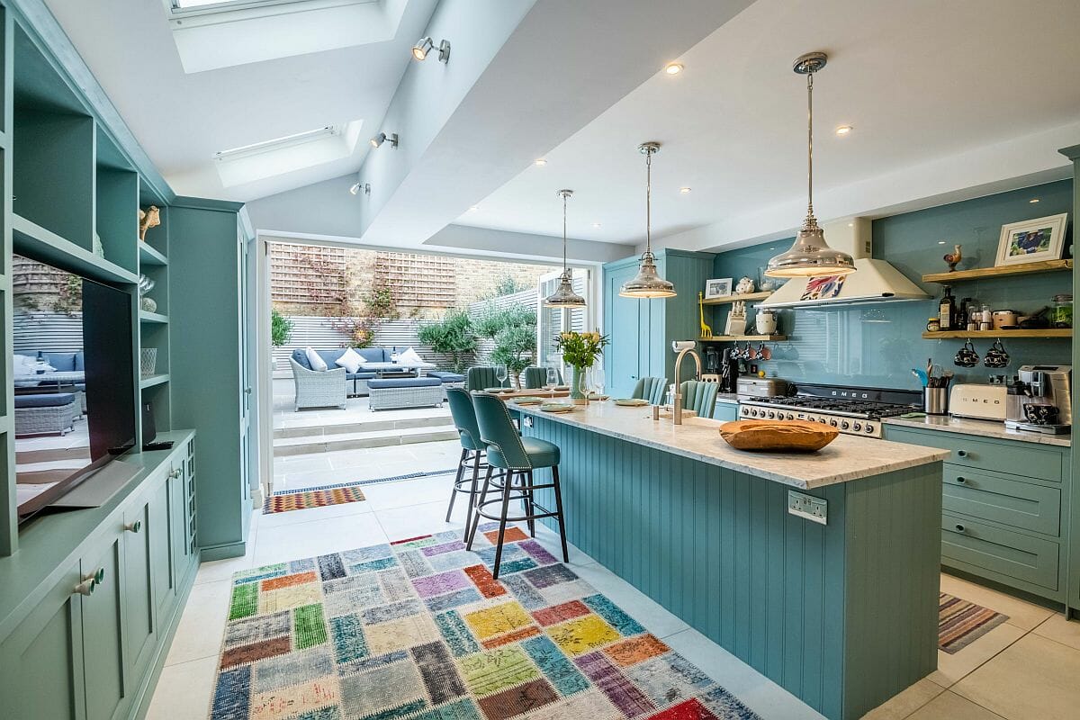 Hình ảnh phòng bếp mùa hè với hệ tủ kệ màu xanh pastel nhẹ nhàng, thảm trải màu sắc tươi mới