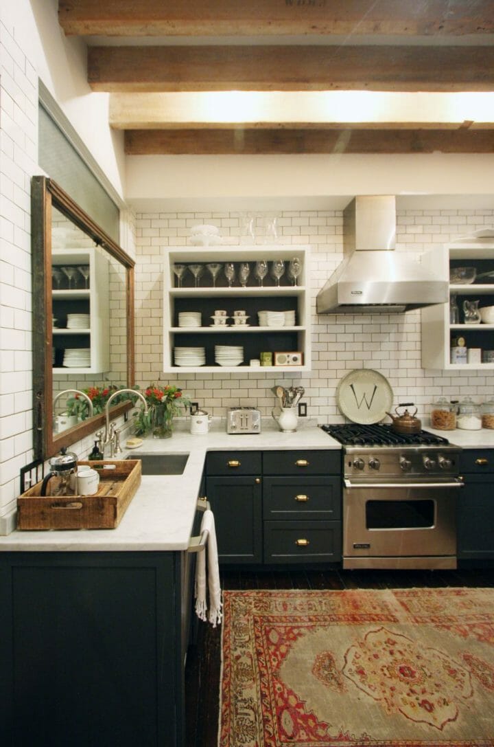 Hình ảnh một góc phòng bếp với tường ốp gạch trắng, tủ sơn đen, gương trên bồn rửa bát
