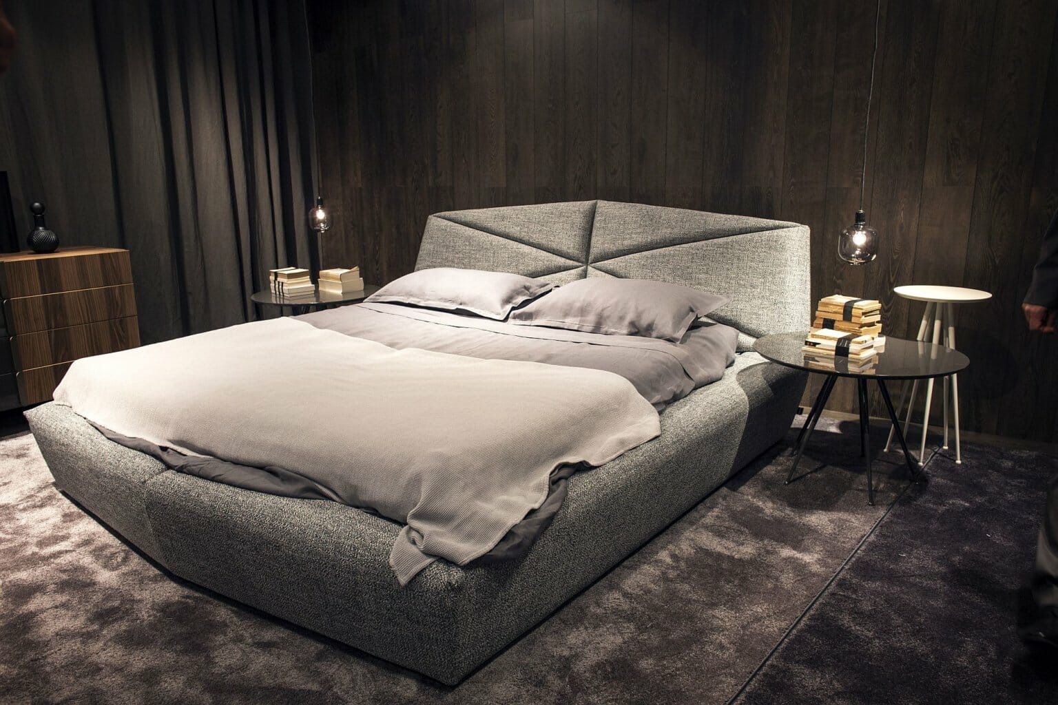 hình ảnh phòng ngủ màu xám chủ đạo với giường nệm êm ái, tủ gỗ, bàn kính tròn, đèn thả mặt dây chuyền