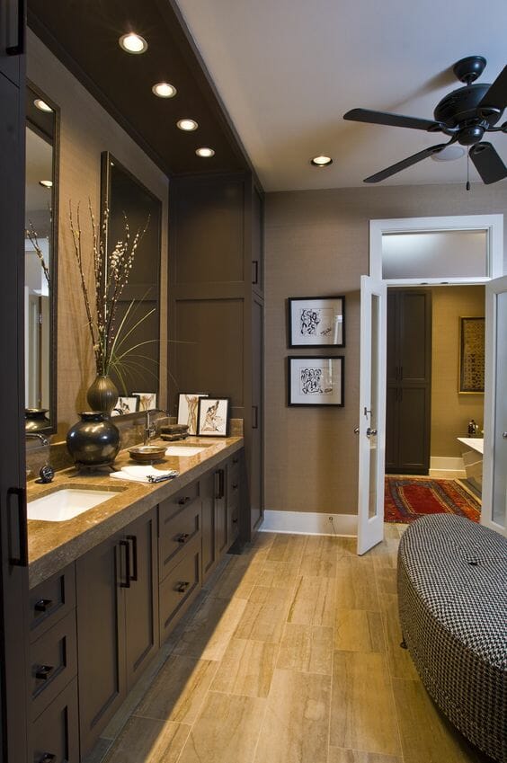 Hình ảnh phòng tắm với trần, tường và hệ tủ lưu trữ màu nâu chủ đạo, đèn led âm trần