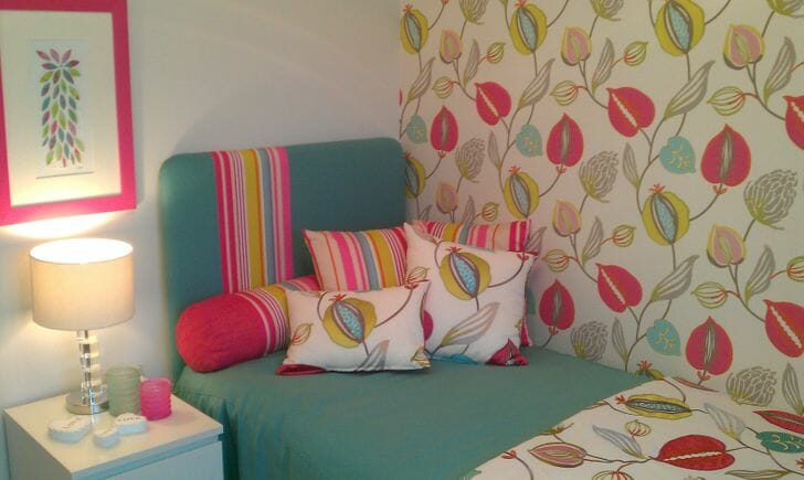 Hình ảnh phòng ngủ với giường màu xanh ngọc, giấy dán tường in họa tiết hoa lá lớn