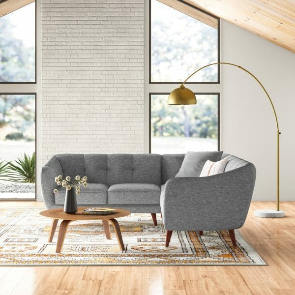 Hình ảnh ghế sofa màu ghi xám, chân gỗ đặt trên thảm trải sàn họa tiết thổ cẩm
