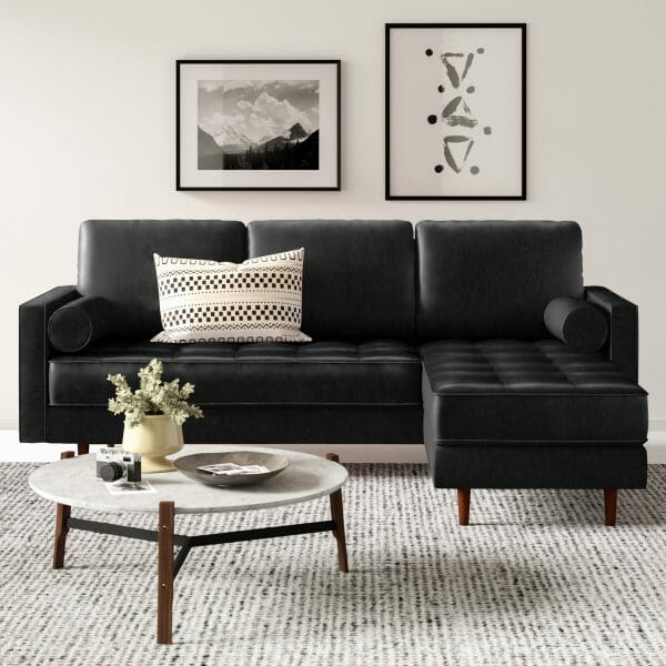 Ghế sofa nhỏ màu đen được bọc bằng da thật với lớp phủ bề mặt mang lại vẻ cổ điển, bàn cà phê nhỏ hình tròn đặt trên thảm trải màu ghi sáng