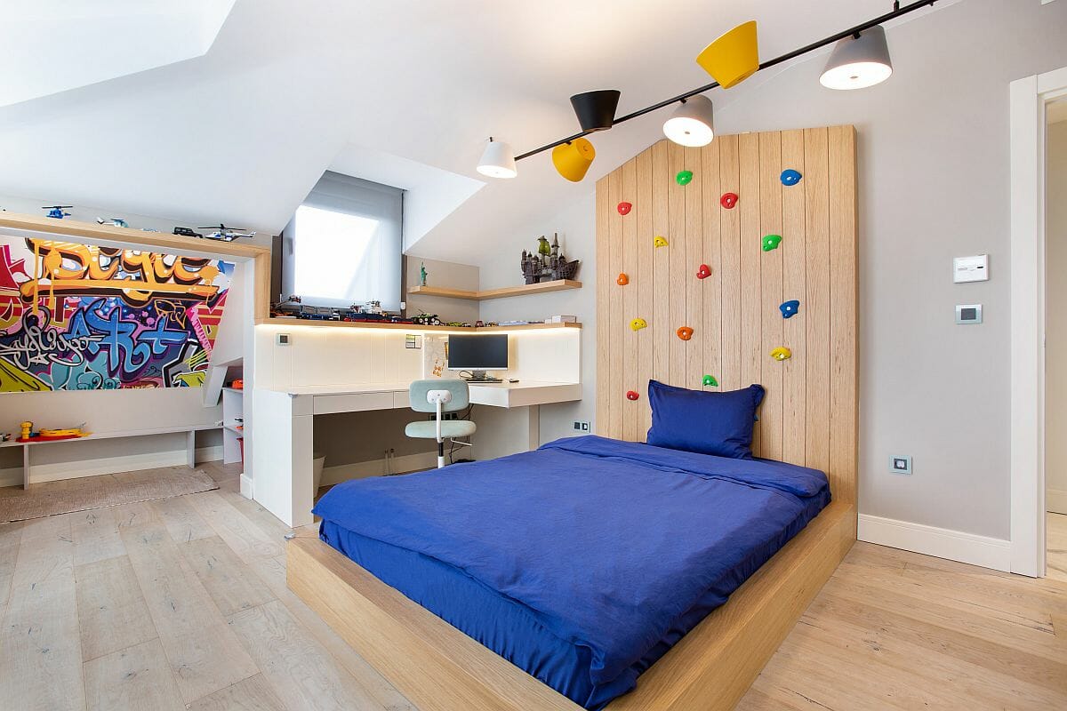 Phòng ngủ trẻ em hiện đại với khu vực học tập gọn xinh, bức tường leo núi thư giãn, nổi bật trên nền tường màu trung tính chủ đạo.