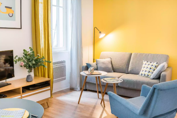Phòng khách nhỏ ấn tượng hơn với bức tường sơn màu vàng tươi sáng.