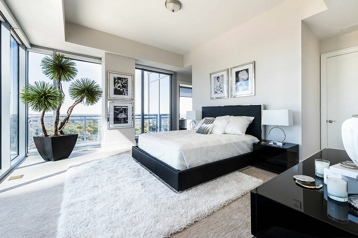 Hình ảnh phòng ngủ rộng rãi với trần và tường sơn trắng, cửa kính cao rộng, cây xanh lớn trang trí ở góc phòng