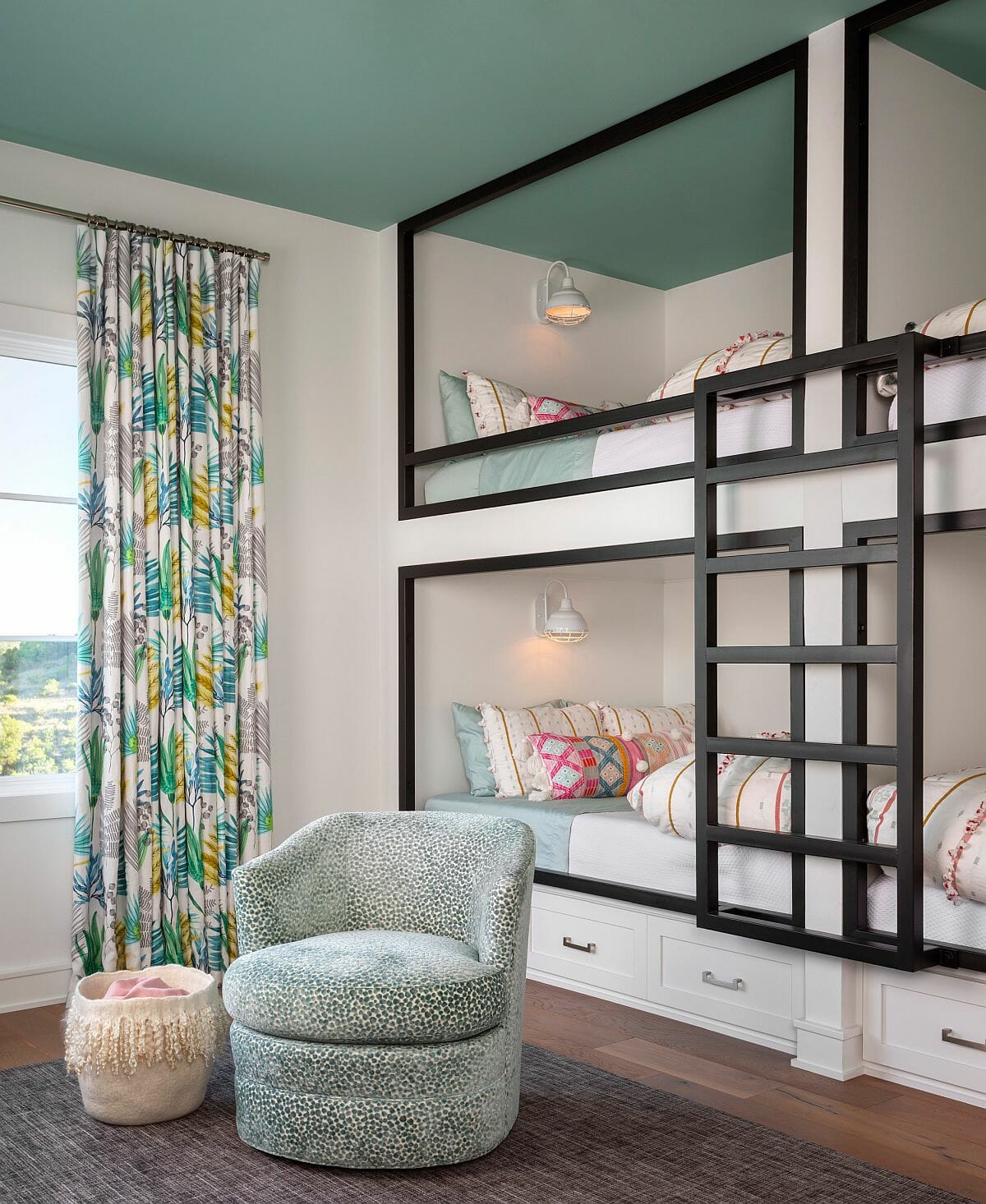 Hình ảnh phòng ngủ trẻ em với giường tầng khung đen trắng, rèm cửa hoa văn nhiệt đới, ghế bành thư giãn, trần sơn màu xanh ngọc