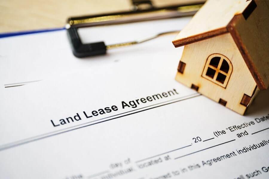 mô hình ngôi nhà thu nhỏ đặt trên bản hợp đồng minh họa cho hợp đồng thuê đất kinh doanh