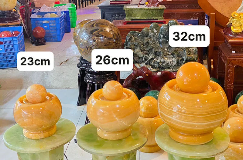 Các mẫu phong thủy luân bằng đá màu vàng với kiểu dáng truyền thống và kích thước đa dạng trưng bày trên kệ